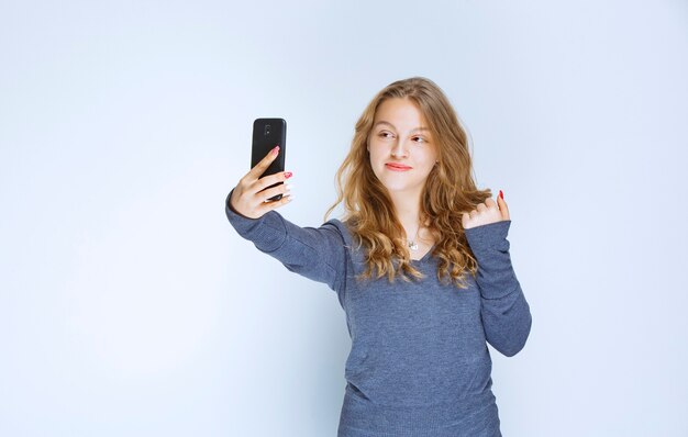 Blonde curly haired girl taking her selfie.