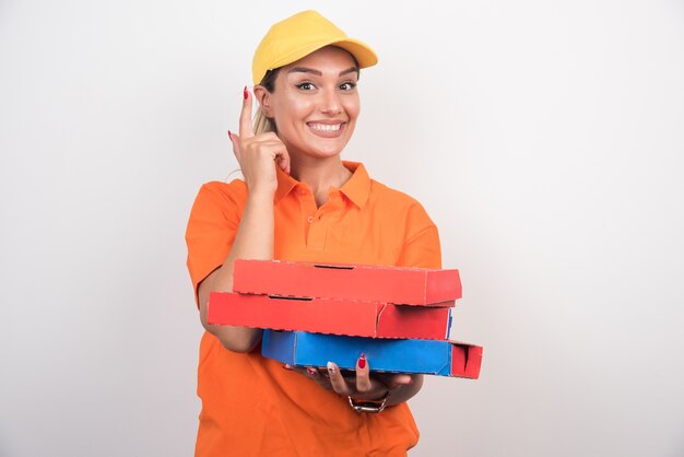 Blonde delivery woman holding pizza boxes pointing up.