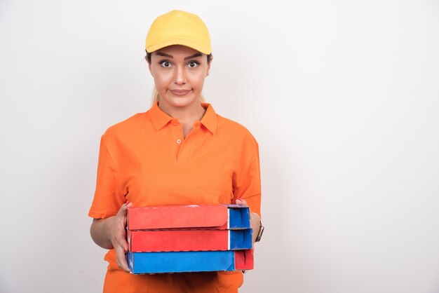 Blonde delivery woman holding pizza boxes with tired expression.