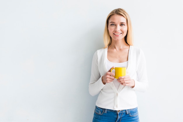 Blonde employee holding cup on white background