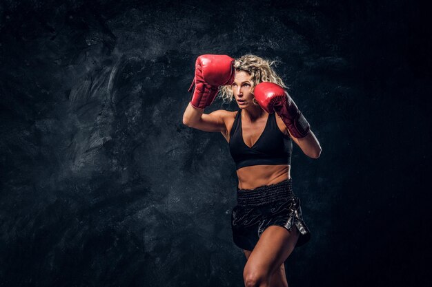 Blonde experienced boxer is demonstrating her tactic attack wearing special gloves.