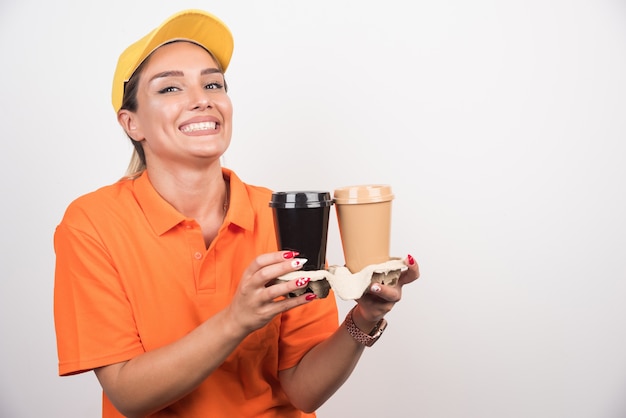 白い壁に2杯のコーヒーを保持している金髪の女性の宅配便。