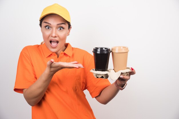 2杯のコーヒーを指している金髪の女性の宅配便。