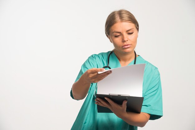 Blonde female doctor in blue uniform checking the history of the patient.