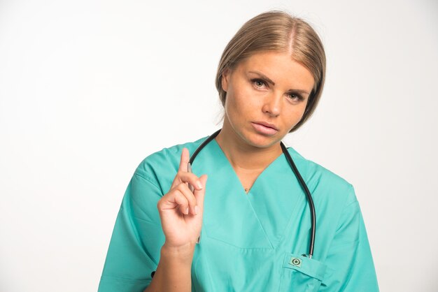 Blonde female doctor in blue uniform with stethoscope in the neck has an idea.