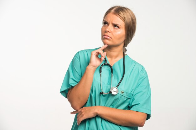 목에 청진 기 파란색 유니폼에 금발 여성 의사는 주저 보인다.