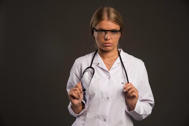 Blonde female doctor with a stethoscope wearing eyeglasses and looking straight. 