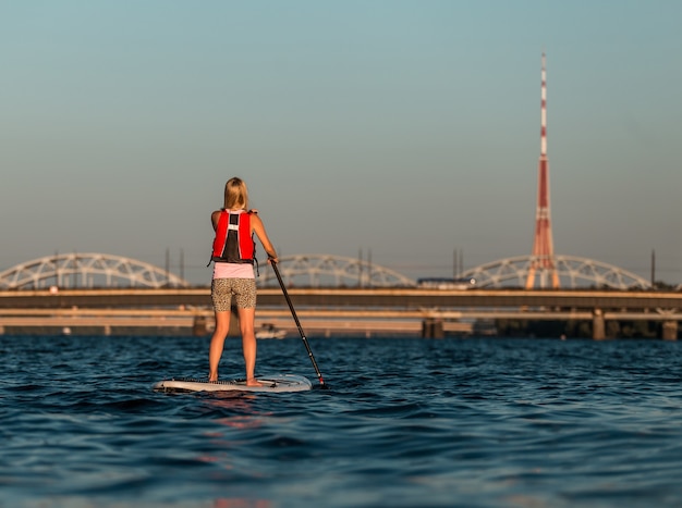 Blonde female on paddleboard on Daugava river, Latvia