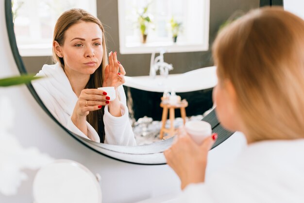 Blonde girl applying cream on her face