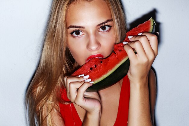 Blonde girl biting a slice of watermelon