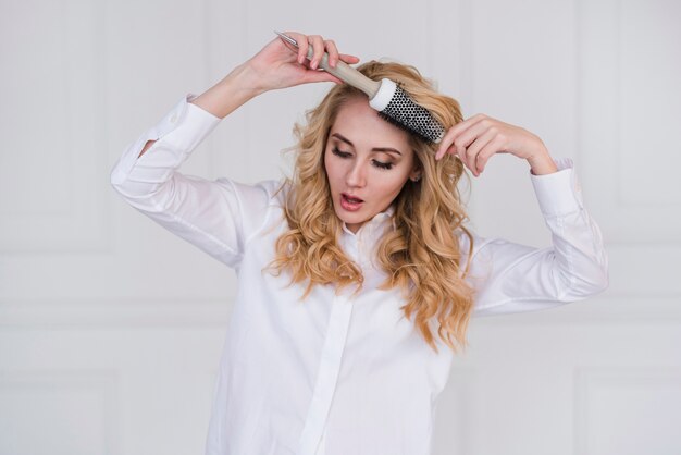 Blonde girl brushing of her hair