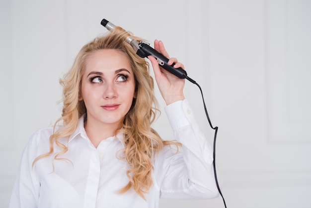 Blonde girl curling her hair