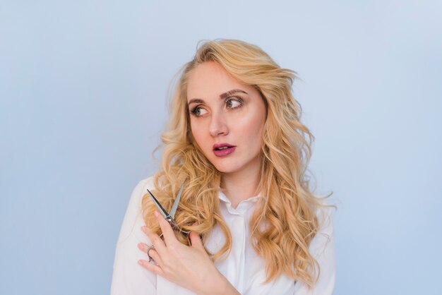 Blonde girl cutting of her hair