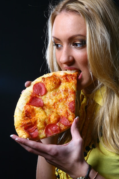 Free photo blonde girl eats pizza