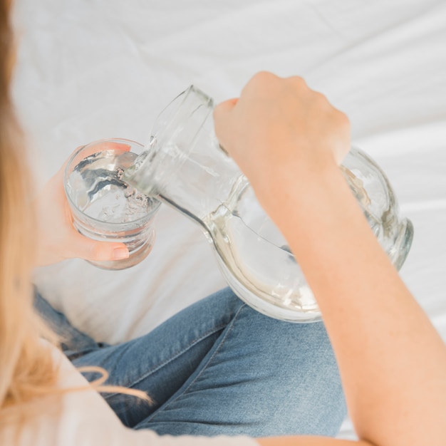 Foto gratuita ragazza bionda che riempie bicchiere d'acqua