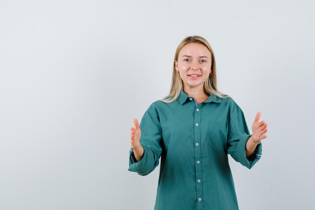 Blonde girl in green blouse showing scales gesture and looking happy