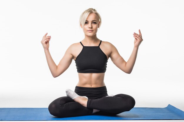 Blonde girl have a relax yoga time after sport practice exercise on the floor sitting on a sport map