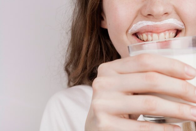 Blonde girl holding a glass of milk close-up