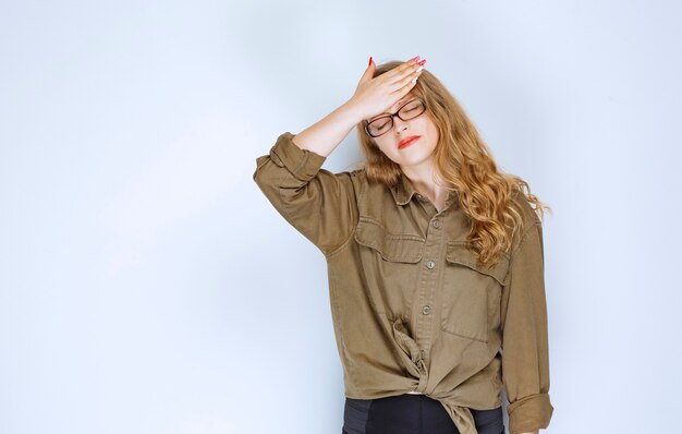 Blonde girl holding her head, looks terrified and exhausted.