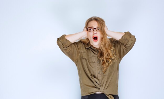 Blonde girl holding her head, looks terrified and exhausted.