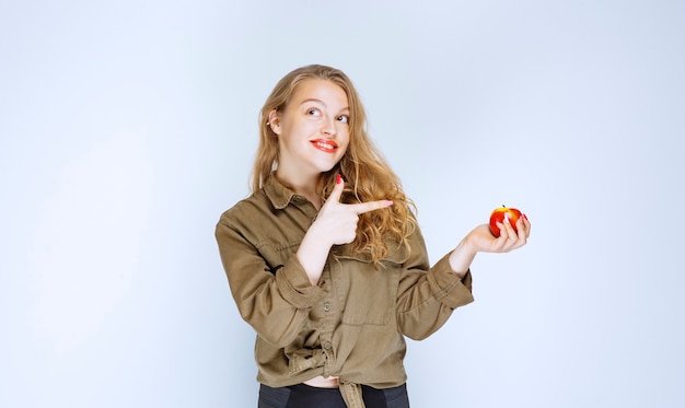 Blonde girl holding and promoting a red peach.