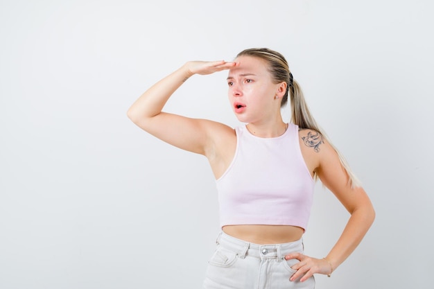 Blonde girl is looking at somebody who is  far from her on white background