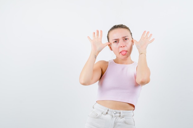 Blonde girl is taking out tounge on white background