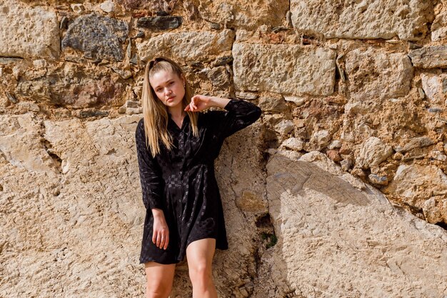 The blonde girl look at the left in black dress on stone background