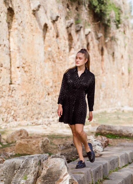 The blonde girl look at the left in black dress on stone background