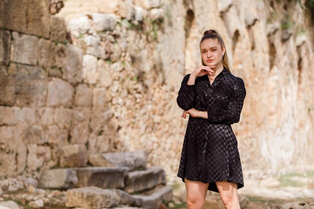 The blonde girl look at the left in black dress on stone background