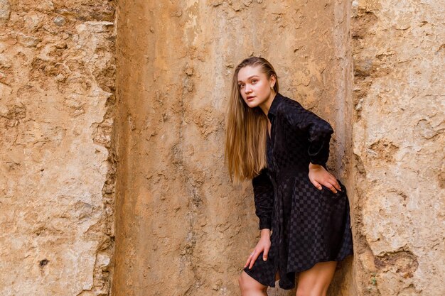 The blonde girl look at the left in black dress on stone background