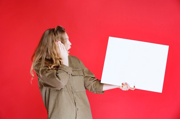 Free photo blonde girl looking to a canvas and gets surprized.