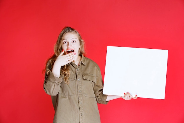 Free photo blonde girl looking to a canvas and gets surprized.