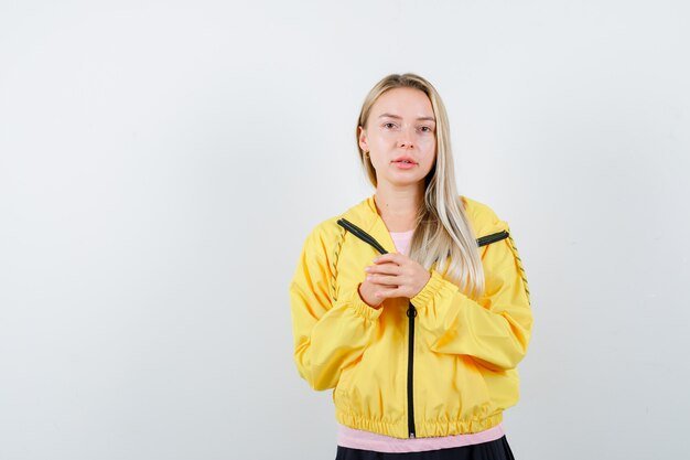 분홍색 티셔츠와 노란색 재킷 손을 쥐고 심각한 찾고 금발 소녀