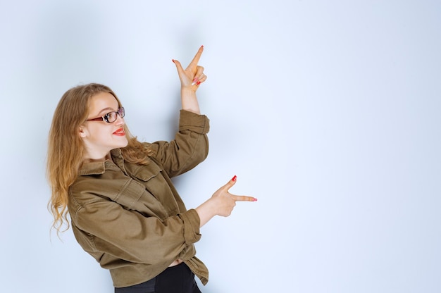 Blonde girl pointing at someone on the right.