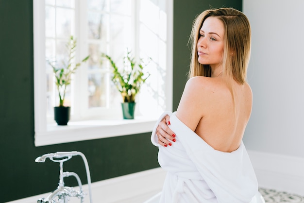 Blonde girl posing in the bathroom with bath robe