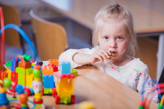 ブロンドの女の子がおもちゃを口に入れる