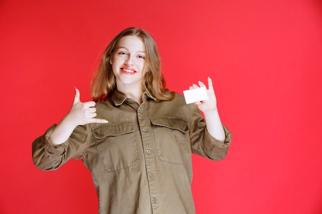 Blonde girl showing her business card and positive hand sign.