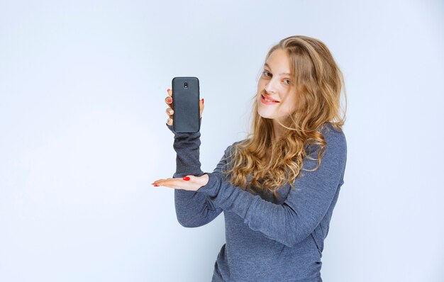 Blonde girl showing her images on new smartphone.
