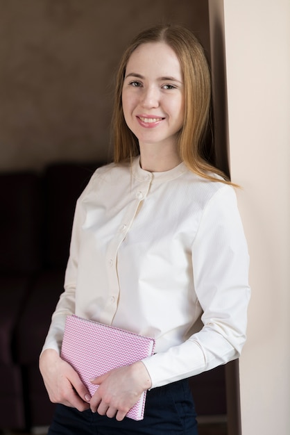 Blonde girl smiling and holding a notebook