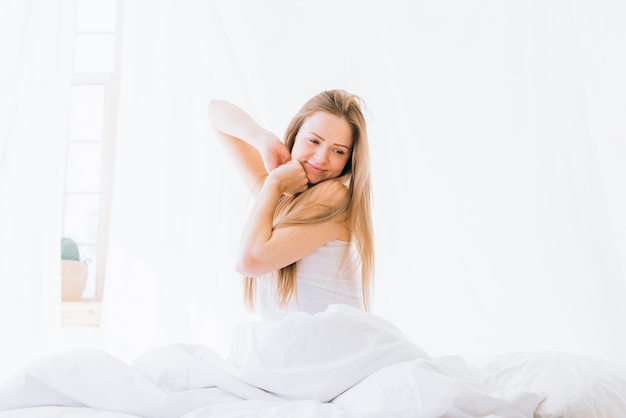 Free photo blonde girl stretching on the bed