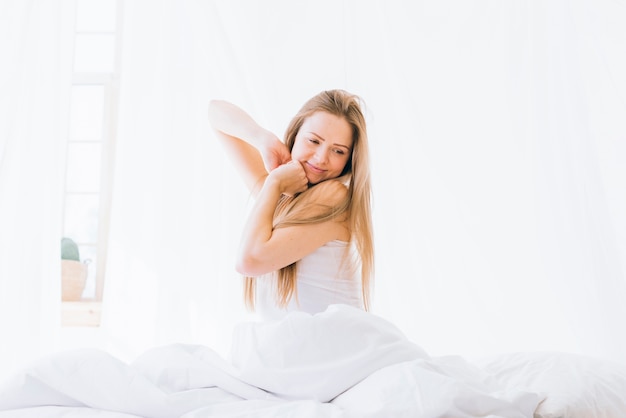 Blonde girl stretching on the bed