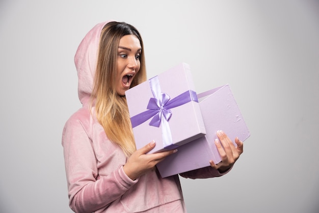 Foto gratuita la ragazza bionda in felpa ha ricevuto una confezione regalo e si sente positivamente sorpresa.