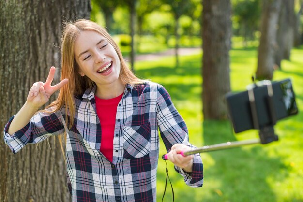 木の隣にselfieを取っているブロンドの女の子