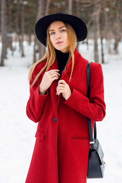 Foto gratuita ragazza bionda che porta cappotto rosso su un campo nevoso