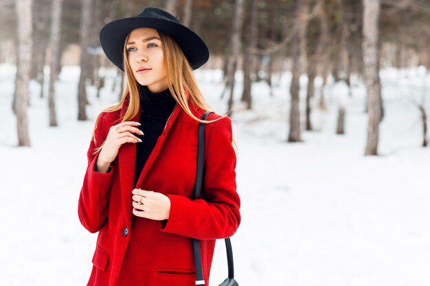 Blonde girl wearing red coat on a snowy field