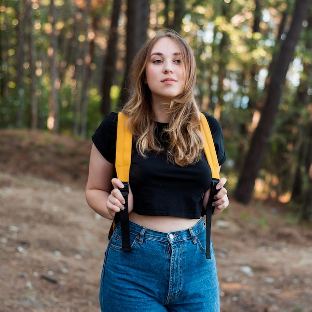 Free photo blonde girl with backpack in forest