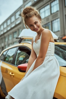 Белокурая девушка с развевающимися волосами на фоне улицы нью-йорка с такси. Premium Фотографии