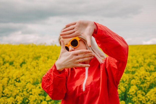 유채 밭에서 선글라스와 빨간 운동복에 금발 프리미엄 사진