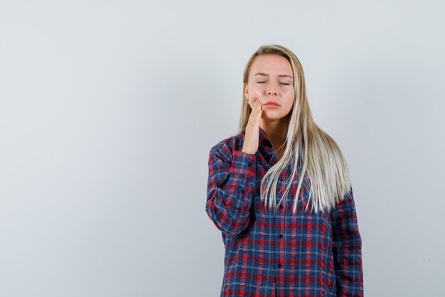 Free photo blonde lady in casual shirt having toothache and looking calm , front view.